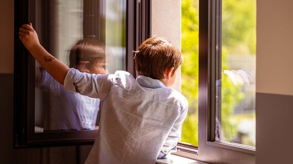 Child looking out of an open window.